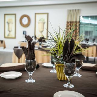 An elegantly set dining table with glassware and a plant centerpiece in a stylish restaurant.