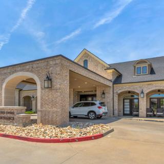 A modern brick building entrance with an arched driveway and a parked car.