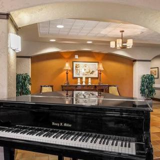 A grand piano in a warmly decorated lobby area with elegant lighting and artwork.