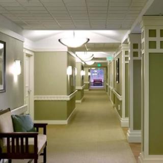 A well-lit hallway with seating and soft green walls.