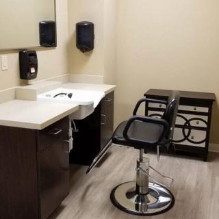 A well-organized salon station featuring a styling chair, sink, and mirror.