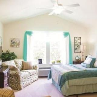 A cozy and well-decorated bedroom with a large window, bed, and sofa.