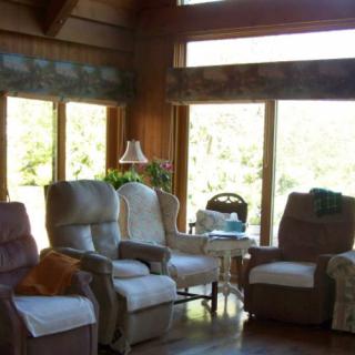 A cozy living room with several recliners facing large windows that let in natural light, featuring a wooden interior design.