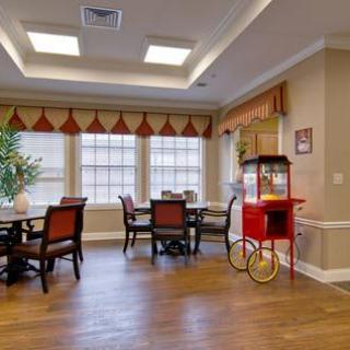 A cozy dining area with wooden tables and chairs, featuring a popcorn machine by the window.