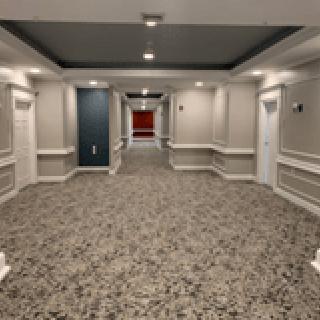A well-lit hallway with patterned carpet and multiple doors.