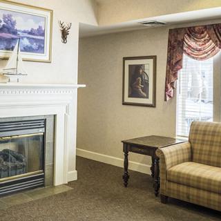 A cozy living room featuring a fireplace, armchair, side table, and decorative artwork.