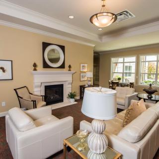 A cozy living room with cream-colored sofas, a fireplace, and elegant decor.