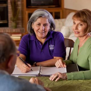 A group of adults engaged in a friendly discussion around a table.
