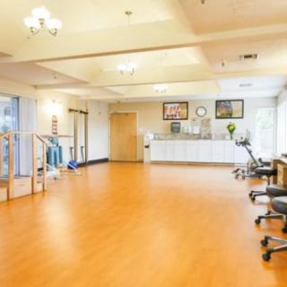 A spacious rehabilitation clinic with exercise equipment and a wooden floor.