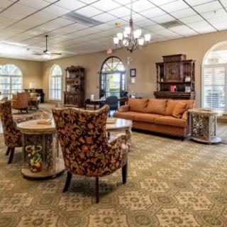 A cozy and traditionally decorated living room featuring a large sofa, patterned chairs, and elegant lighting.