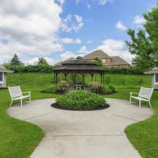 A serene garden with a gazebo and benches surrounded by lush greenery.