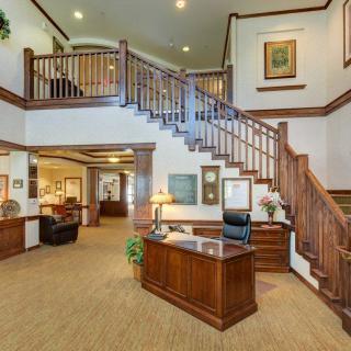 A well-appointed office lobby featuring a reception desk and a grand wooden staircase.