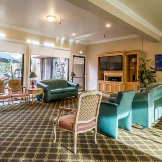 A spacious living room with comfortable sofas, a TV, and patterned carpet.