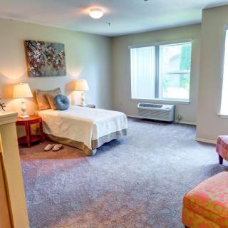 A cozy bedroom with a single bed, bedside tables with lamps, and large windows.