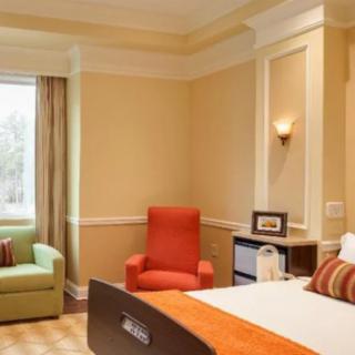 A cozy hotel room featuring a comfortable bed, an armchair, and a window with natural light.