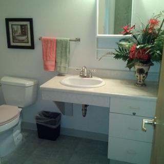 A clean and tidy bathroom featuring a sink, mirror, and various decorations including towels and a floral arrangement.
