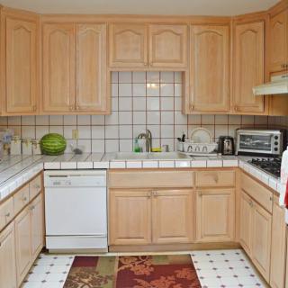 A spacious kitchen with wooden cabinets and tiled backsplash, featuring modern appliances.