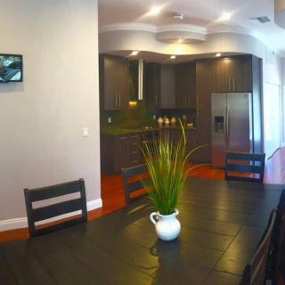 A modern dining area with a sleek table and chairs, featuring a view into the kitchen.