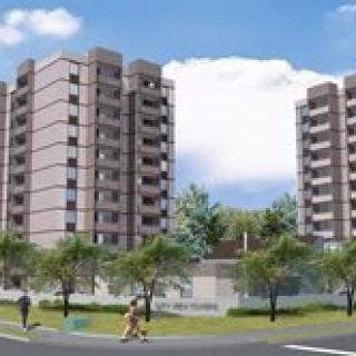 A view of two modern apartment buildings surrounded by trees and under a blue sky.