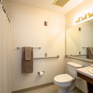 A clean and simple bathroom with a toilet, sink, mirror, and towel rack.
