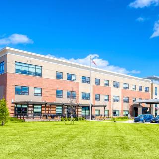 A modern school building under a bright blue sky.