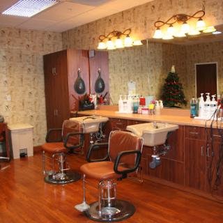 A cozy hair salon featuring stylish chairs and a well-lit mirror area.