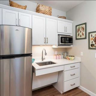 A modern kitchen with white cabinets, a stainless steel refrigerator, and decorative wall art.