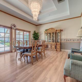 An elegantly designed dining room with a large chandelier, wooden flooring, and classic furniture.