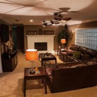 A cozy living room featuring a leather sofa, warm lighting, and a fireplace.