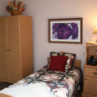 A cozy bedroom with a single bed, wardrobe, and decorative artwork on the wall.