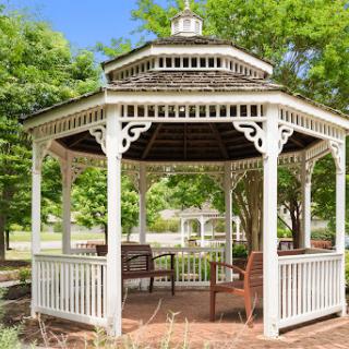 A beautiful white gazebo surrounded by lush greenery.