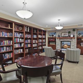 Cozy library with bookshelves, a fireplace, and seating area.