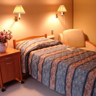 A cozy bedroom featuring a neatly made bed, bedside lamps, and a comfortable chair.