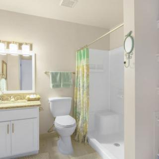 A clean and bright bathroom with a shower, toilet, and sink.