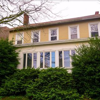 A charming two-story house surrounded by lush greenery.