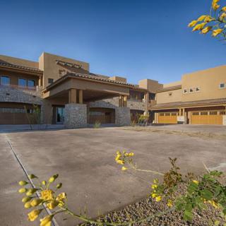 A modern building with a spacious driveway and landscaped surroundings on a sunny day.