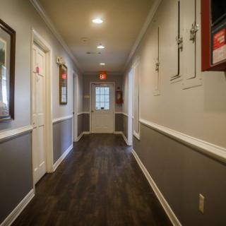 A well-lit indoor hallway with doors and dark flooring.