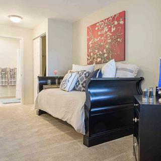 A cozy and stylish bedroom with a dark wooden bed, adorned with pillows and a colorful artwork on the wall.