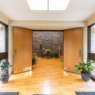 A modern entrance with wooden doors, indoor plants, and a tiled wall.