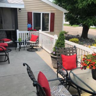 Cozy patio setting with red-cushioned chairs and potted plants outside a house.