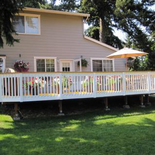 A backyard view of a house with an elevated deck and outdoor seating area.