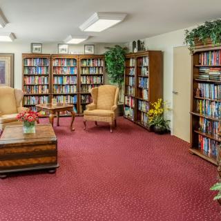 A cozy library room with bookshelves, armchairs, and a coffee table.