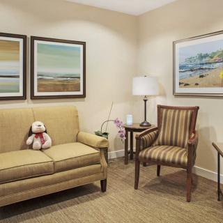 A cozy living room with a sofa, armchair, and decorative paintings.