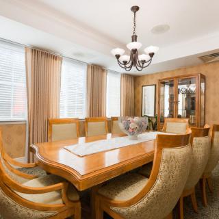 A beautifully designed dining room with an elegant wooden table, upholstered chairs, and a chandelier.