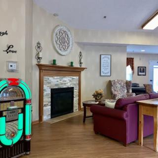 A cozy living room with a jukebox and a fireplace, featuring comfortable seating and elegant decor.