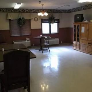 A furnished room with chairs, tables, and a television.