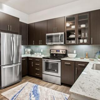 A modern kitchen with stainless steel appliances and dark cabinetry.
