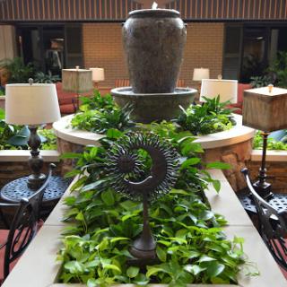 A serene indoor fountain surrounded by lush greenery and elegant lighting.