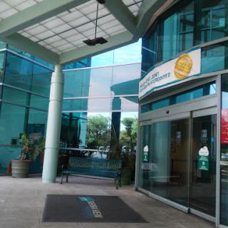 The entrance of a modern glass building with clear signage.