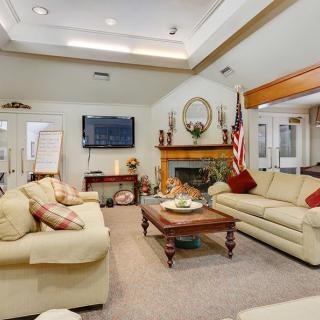A cozy living room featuring comfortable sofas, a television mounted on the wall, and a fireplace adorned with decorative items.